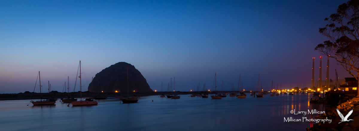 Morro Bay Harbor with Morro Rock on the horizon, just after the sun has gone down.